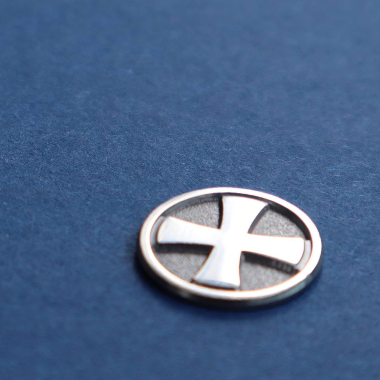 Seurakuntatyön hopeinen ansiomerkki sinisen kankaan päällä.