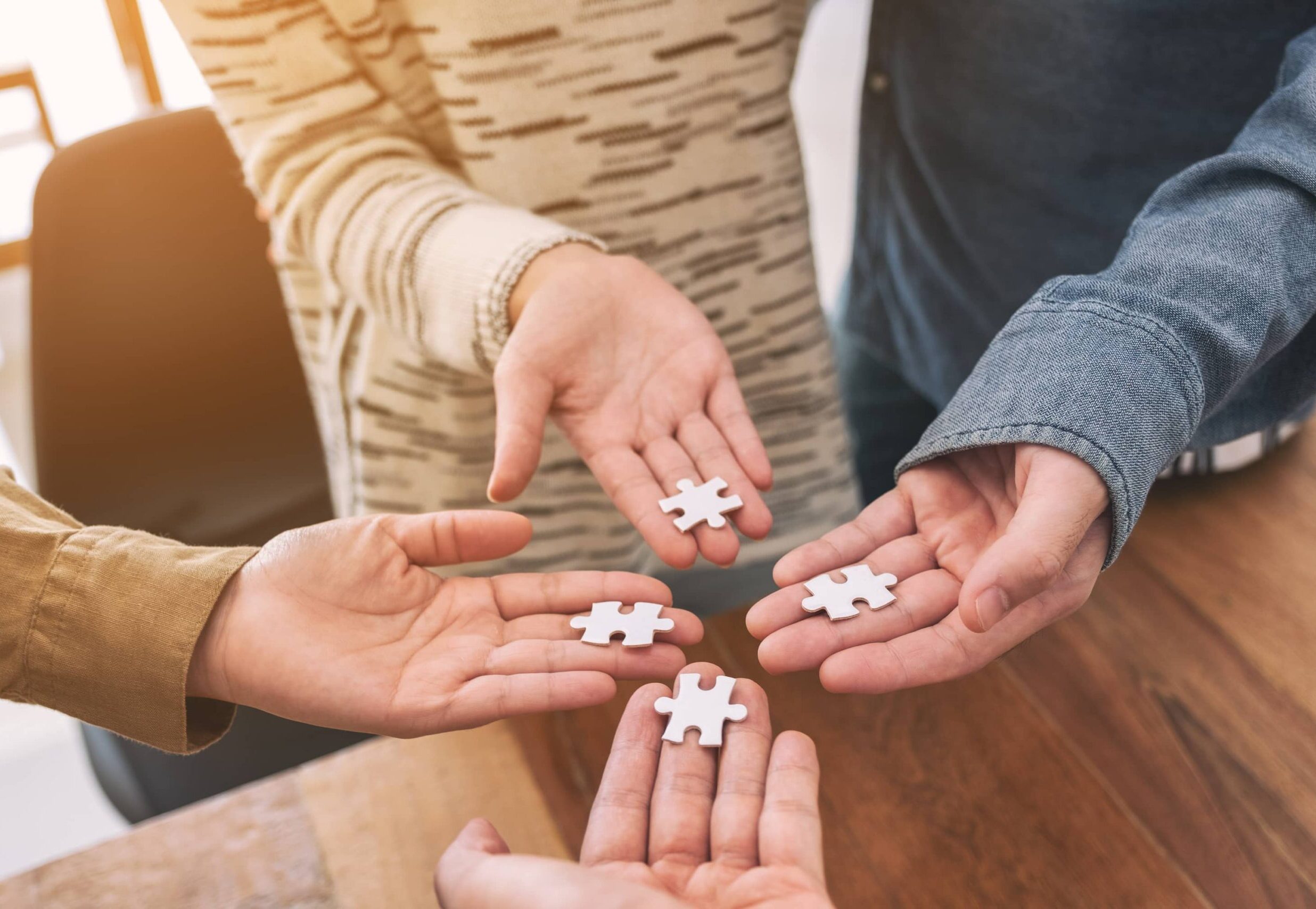 Ihmisten kädet pitävät palapelin paloja, kuvaten yhteistyötä, kohtaamista ja yhteisen ymmärryksen rakentamista.